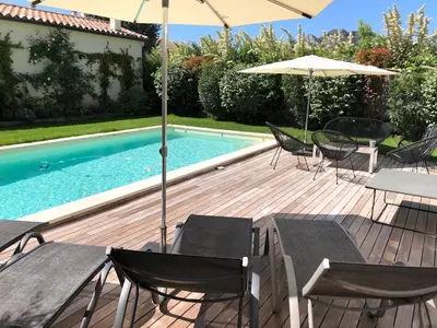a deck with chairs and an umbrella and a pool at Maison contemporaine dans le village d'Eygalières in Eygalières