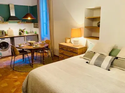 a bedroom with a bed and a table and a kitchen at Appartement de charme au coeur du vieux Aix. in Aix-en-Provence