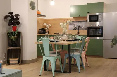 a kitchen with a table and chairs and a refrigerator at Chez Franck et Gisele in LʼIsle-sur-la-Sorgue