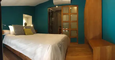 a bedroom with blue walls and a bed with striped pillows at AJOUCADOU le nid in Lourmarin