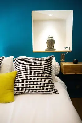 a bed with a black and white pillow and a blue wall at AJOUCADOU le nid in Lourmarin