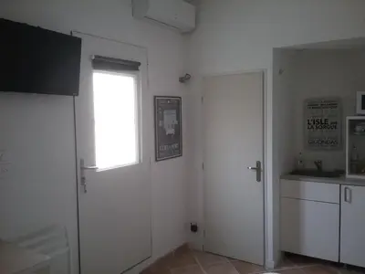 a kitchen with white walls and a window and a door at UNE CHAMBRE EN VILLE in LʼIsle-sur-la-Sorgue