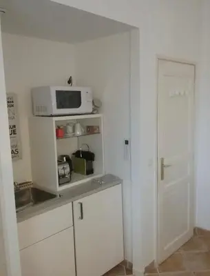 a kitchen with a microwave on top of a counter at UNE CHAMBRE EN VILLE in LʼIsle-sur-la-Sorgue