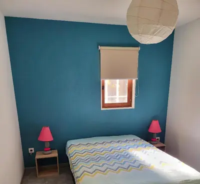 a bedroom with a blue wall and a bed with two lamps at Le nid’Ange in Velleron