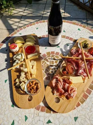two wooden cutting boards with food and a bottle of wine at Le nid’Ange in Velleron