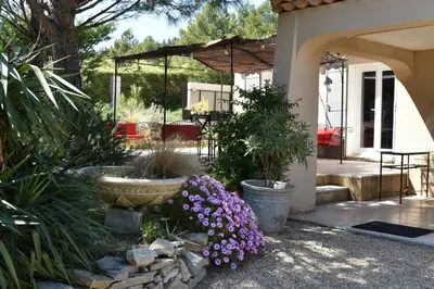 a patio with purple flowers and an umbrella at magnificent detached villa with heated swimming pool and jacuzzi, in aureille, in the alpilles – 8 people in Aureille