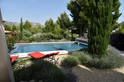 a swimming pool with two red chairs and a tree at magnificent detached villa with heated swimming pool and jacuzzi, in aureille, in the alpilles – 8 people in Aureille