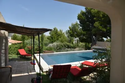 a swimming pool with a group of red chairs next to it at magnificent detached villa with heated swimming pool and jacuzzi, in aureille, in the alpilles – 8 people in Aureille