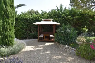 a gazebo with an umbrella in a garden at magnificent detached villa with heated swimming pool and jacuzzi, in aureille, in the alpilles – 8 people in Aureille