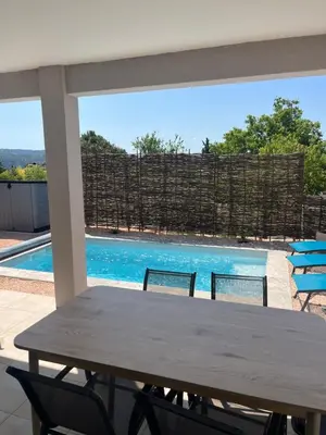a table and chairs in front of a swimming pool at Les jardins de la Gravière à 5 mn de Lourmarin avec piscine privée in Puyvert