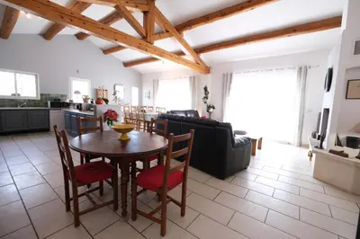 a kitchen and living room with a wooden table and chairs at pretty holiday rental with swimming pool in isle-sur-la-sorgue, in the département of vaucluse, in provence 4 people in LʼIsle-sur-la-Sorgue