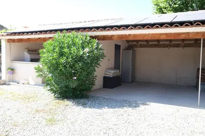 a house with a bush in front of a garage at pretty holiday rental with swimming pool in isle-sur-la-sorgue, in the département of vaucluse, in provence 4 people in LʼIsle-sur-la-Sorgue