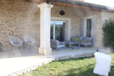a patio with chairs and tables and a pillar at La Cath - Villa avec piscine - Gordes in Gordes