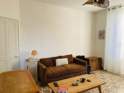 a living room with a brown couch and a table at Gîte Mas La Bohème Piscine Parking Privé L'Isle-Sur-La-Sorgue in LʼIsle-sur-la-Sorgue