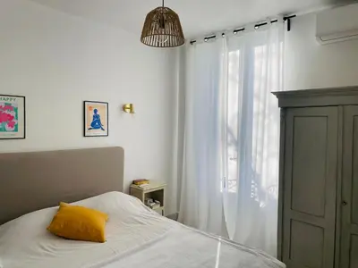 a bedroom with a bed with a yellow pillow and a window at Gîte Mas La Bohème Piscine Parking Privé L'Isle-Sur-La-Sorgue in LʼIsle-sur-la-Sorgue