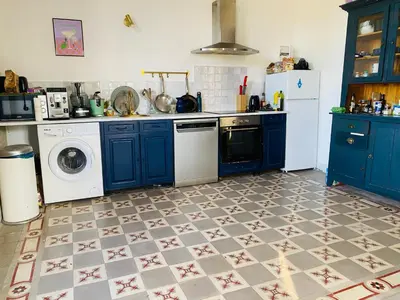 a kitchen with blue cabinets and a washing machine at Gîte Mas La Bohème Piscine Parking Privé L'Isle-Sur-La-Sorgue in LʼIsle-sur-la-Sorgue