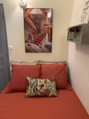 a bed with red pillows and a picture on the wall at Lou Magnan in LʼIsle-sur-la-Sorgue