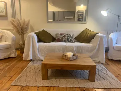 a living room with a white couch and a coffee table at Lou Magnan in LʼIsle-sur-la-Sorgue
