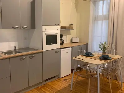 a kitchen with a small table and a white appliance at Lou Magnan in LʼIsle-sur-la-Sorgue