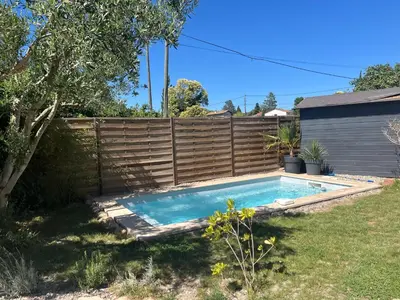 a swimming pool in a yard next to a fence at Sasha'blue-terrasse jardin-park-clim-piscine in LʼIsle-sur-la-Sorgue