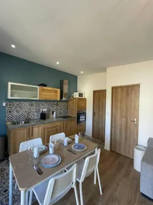 a dining room table with chairs and a kitchen at Logement entier avec jacuzzi en provence in Le Thor