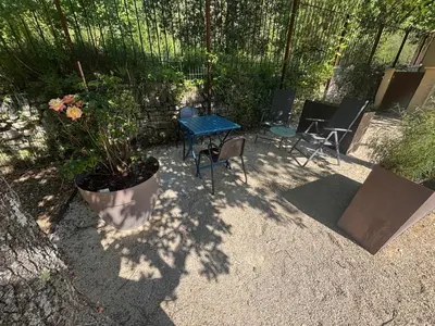 a patio with a table and chairs and a potted plant at Studio cosy à Lagnes avec Piscine au milieu des oliviers in Lagnes