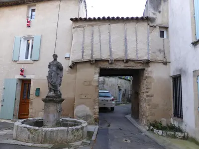 a statue in front of a building with a tunnel at La Reynière du Sud Luberon in La Bastide-des-Jourdans