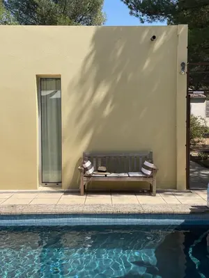 a bench next to a building next to a swimming pool at La Beaume in Blauvac
