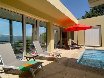 a patio with chairs and an umbrella and a pool at La Beaume in Blauvac