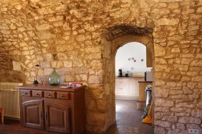 a kitchen with an archway in a stone wall at Les Grottes in Sivergues