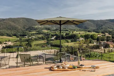 a wooden table with an umbrella and chairs with a view at Le Pavadou B&B in Méthamis