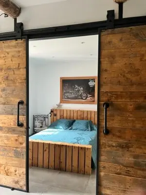 a bedroom with a bed inside of a glass door at MAS DE VILLE AVEC PISCINE DANS SON COCON DE VERDURE - ESPRIT INDUSTRIEL in Carpentras