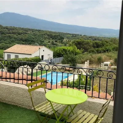 a balcony with a table and chairs and a pool at Le Tavan in Crillon-le-Brave