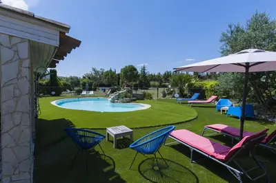 a patio with chairs and an umbrella and a pool at Gîte Petit Luberon chez Manon en Luberon - Vacation rental in guest house in Lagnes