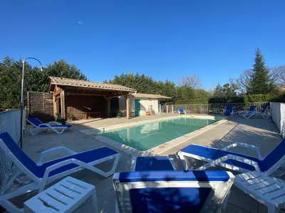 a swimming pool with blue chairs and a house at Gîte Lou Pastre in Aureille