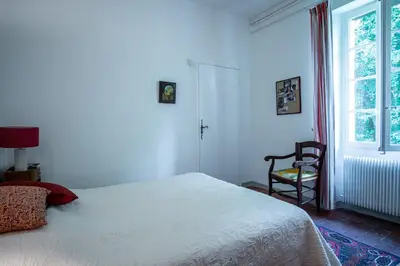 a bedroom with a bed and a chair and a window at Le Mas de Jalique - Isle-sur-la-Sorgue in LʼIsle-sur-la-Sorgue