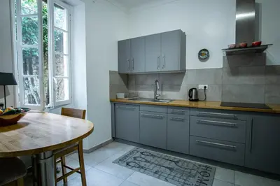 a kitchen with gray cabinets and a table and a tableablish at Le Mas de Jalique - Isle-sur-la-Sorgue in LʼIsle-sur-la-Sorgue
