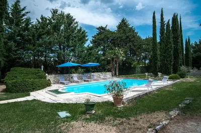 a pool with chairs and umbrellas in a yard at Le Mas de Jalique - Isle-sur-la-Sorgue in LʼIsle-sur-la-Sorgue