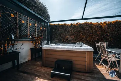 a hot tub on a deck with a table and chairs at Villa Moderne avec Jacuzzi proche d'Avignon in Le Thor
