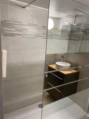 a bathroom with a glass shower with a sink at La Ferme l'Etang in Vachères