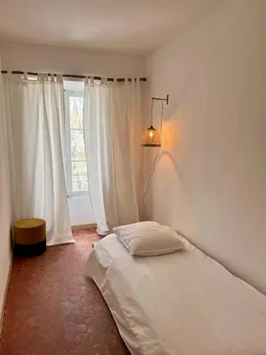 a bedroom with a bed and a lamp and a window at La Maison de Lola in Carpentras