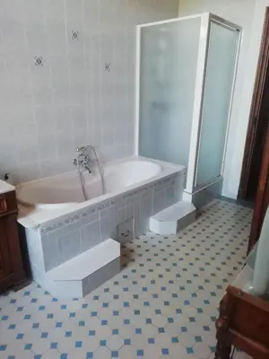 a bathroom with a tub and a shower and a tiled floor at Chez Fleur in Avignon