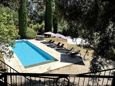 a swimming pool with lounge chairs and umbrellas at La Terrasse Collongue in Lourmarin