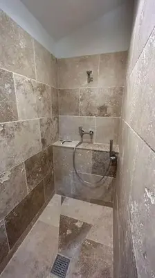 a tiled bathroom with a shower with a hose at La Terrasse Collongue in Lourmarin
