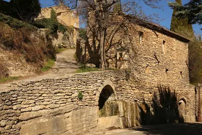 a stone wall next to a road next to a building at La petite Maison de Gordes in Gordes