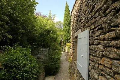 a stone wall with a white door on a path at La petite Maison de Gordes in Gordes
