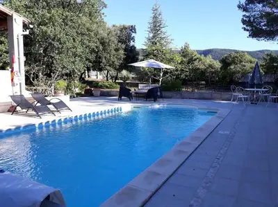 a pool with chairs and a table and an umbrella at Villa le Bosquet en Luberon. in Ménerbes