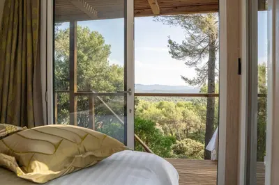 a bedroom with a bed and a large window at Le Chant des Pins Lodge & Spa Massif de l'Etoile in Saint-Marc-Jaumegarde