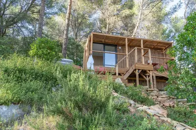 a wooden house on a hill with trees at Le Chant des Pins Lodge & Spa Massif de l'Etoile in Saint-Marc-Jaumegarde