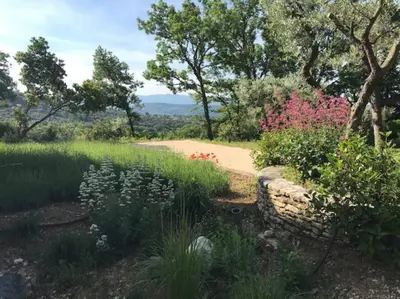 a garden with flowers and a stone wall at Chante Coucou in Saint-Saturnin-les-Apt
